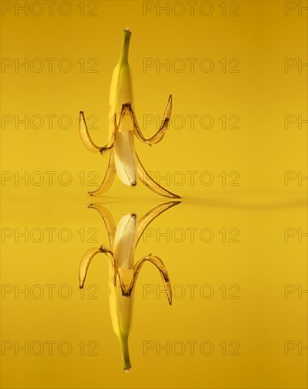 Banana with peel against a yellow background