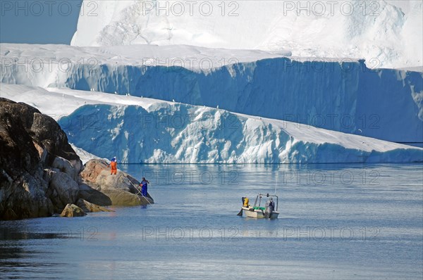 Boat in front of huge iceberg