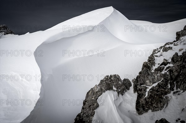 Snow cornice against a dark sky at the summit of Toreck