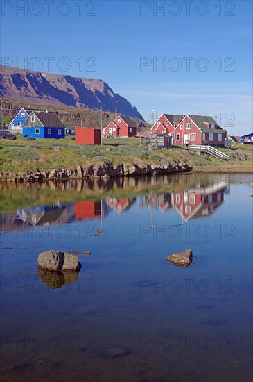Wooden houses reflected in a body of water on a calm summer evening
