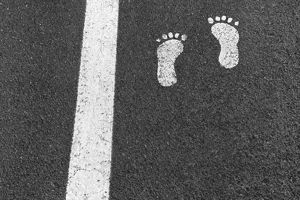 White line and two footprints on asphalt