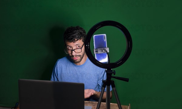 Young man with laptop making video blog
