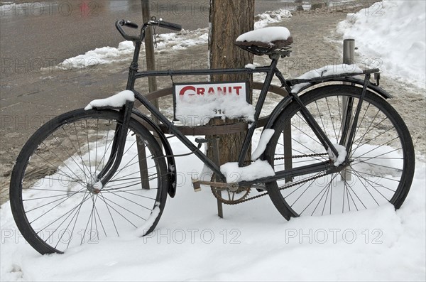 Black bicycle in the snow advertises Granit workshop