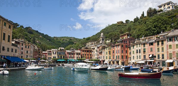 Panoramic photo of harbour of former fishing village Portofino with small boats in sheltered bay and pastel coloured houses