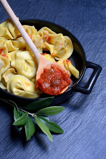 Pasta in pot and cooking spoon with tomato sauce