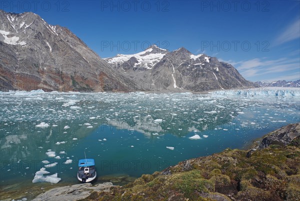 Small boat in a fjord with ice and icebergs