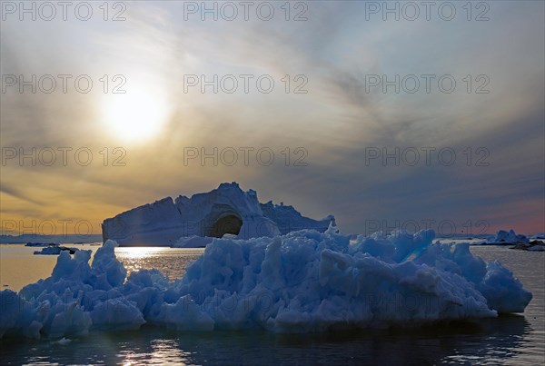 Huge icebergs and drift ice in the glow of the midnight sun