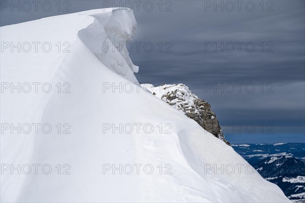 Snow cornice against a dark sky at the summit of Toreck