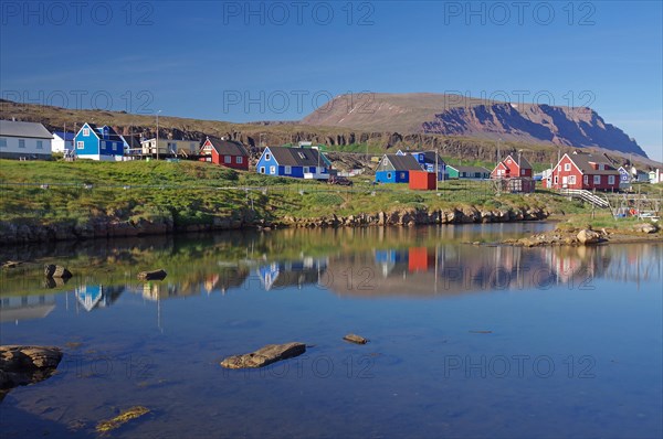 Wooden houses reflected in a body of water on a calm summer evening