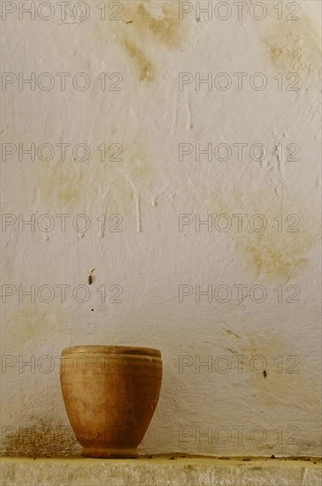 Clay jug in front of white wall in cave house