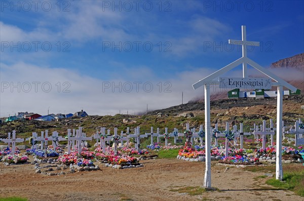 Wooden crosses in front of graves decorated with colourful artificial flowers