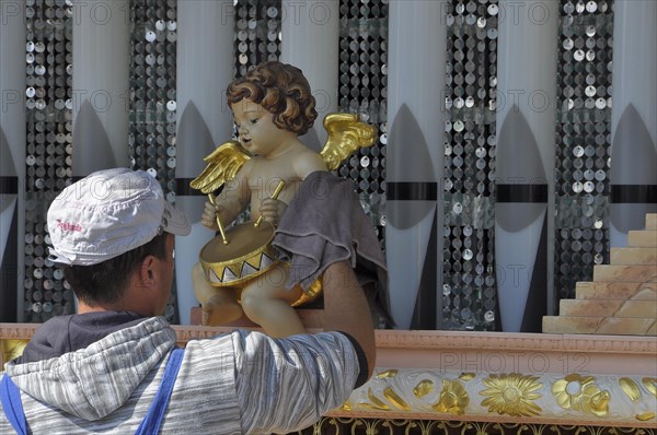 Man cleaning angel with drum from hurdy-gurdy at historic Oktoberfest