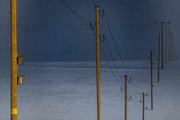 Electricity pylons in winter landscape against dramatic sky