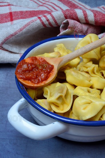 Pasta in pot and cooking spoon with tomato sauce