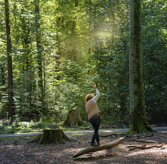 Woman balancing on a log in the forest