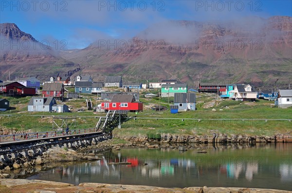 Simple bridge leading to houses reflected in a body of water