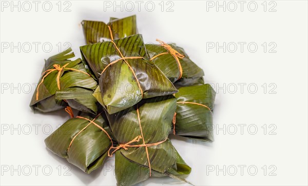 Close up of nacatamales with banana leaves on white background