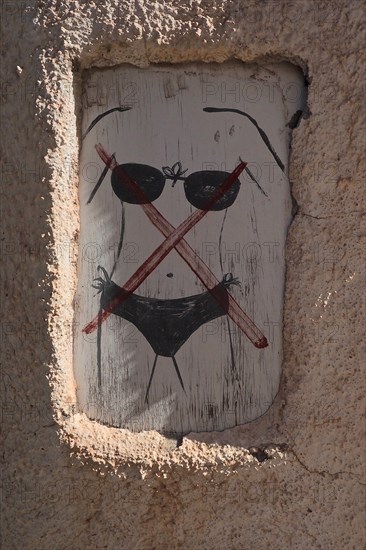 Wooden sign with bikini forbidden on wall of restaurant