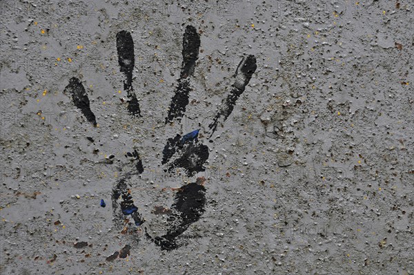 Black handprint with paint on grey house wall