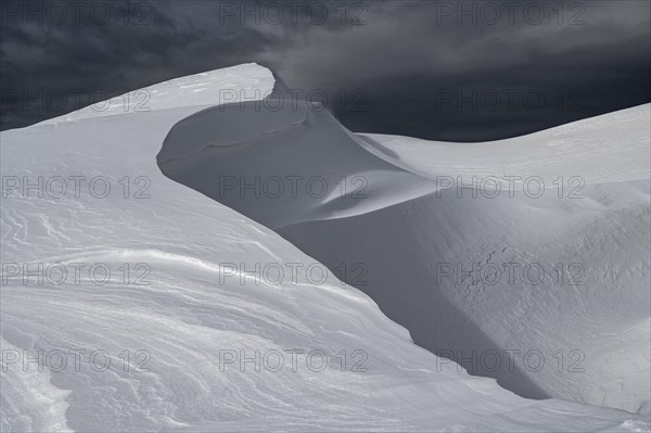 Snow cornice against a dark sky at the summit of Toreck