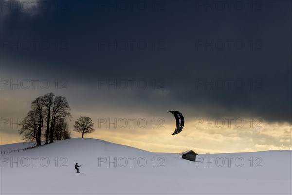 Kite surfers in winter landscape in front of dramatic sky