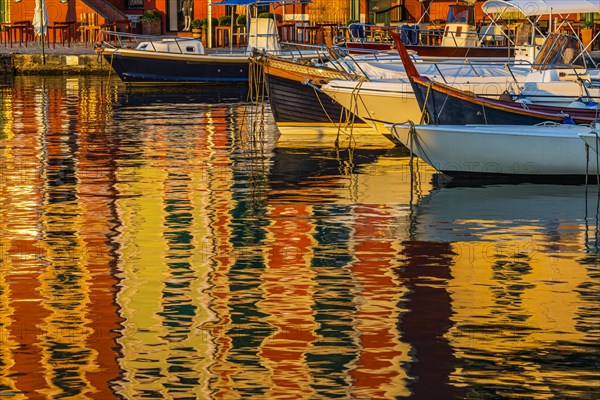 Pastel-coloured house facades are reflected in the harbour of Portofino