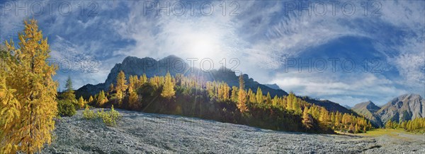 Glowing autumnal mountain forest below the Lamsenjoch massif with bizarre cloudy sky