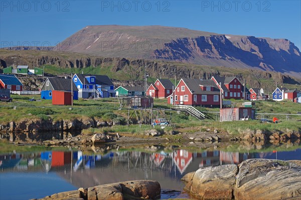 Wooden houses reflected in a body of water on a calm summer evening