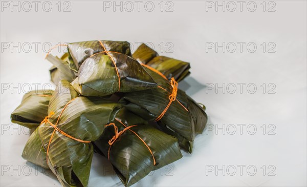 Close up of nacatamales with banana leaves on white background