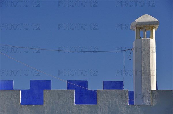 Chimney with white and blue battlements against the blue sky