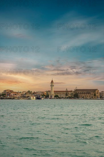 Sunset view over the sea to a Mediterranean town. St. Dionisius Church