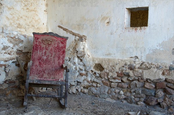 Stained rocking chair in front of old wall in abandoned house