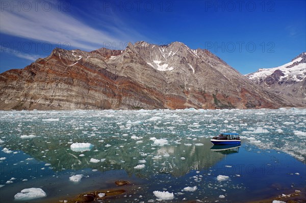 Small boat in a fjord with ice and icebergs