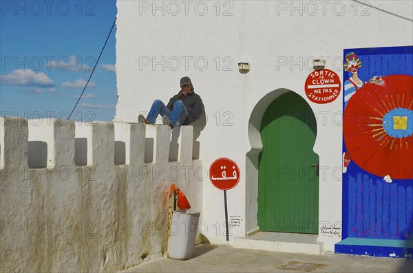 Young man sunbathing on city wall