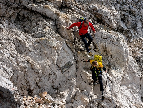 Climbers climb the metal ladder to the summit plateau of the Zugspitze