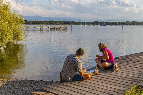 Man and woman sitting on the jetty in the evening