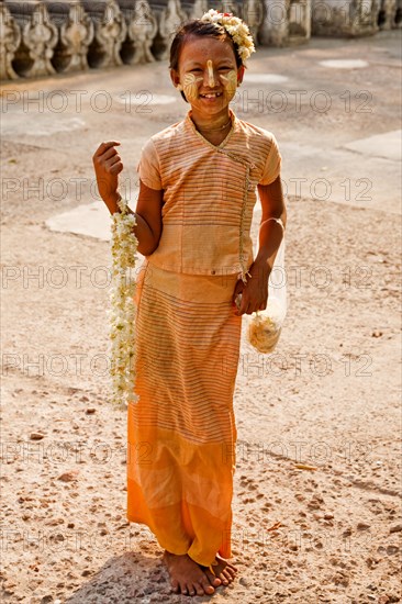 Girl with flower necklace in front of Shwenandaw Monastery