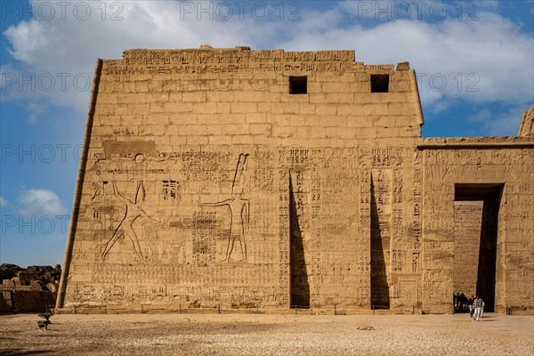 1st pylon in the funerary temple decorated with oversized relief depictions showing the pharaoh in typical displays of power slaying enemies in front of a deity