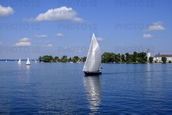 White sailing boat in front of Fraueninsel with Frauenwoerth Monastery