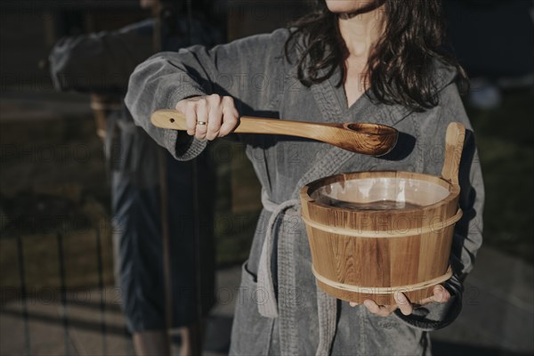 Woman with infusion tub in front of the sauna