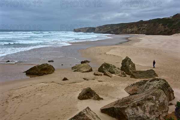 Lonely walker on the beach on the Atlantic Ocean in stormy weather