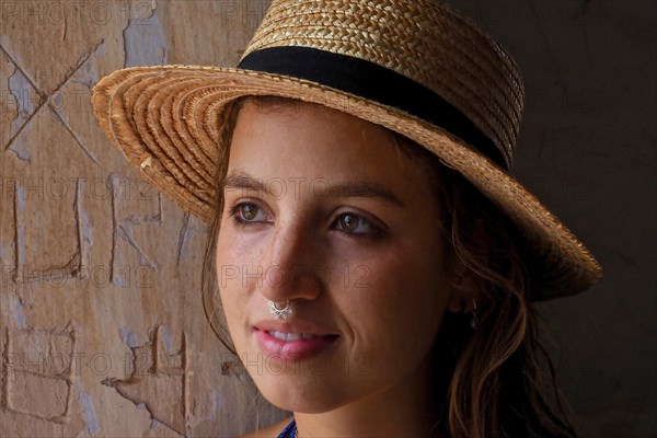 Young woman with straw hat and nose piercing sweats