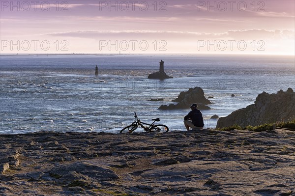 Cyclist sitting on rocky coast