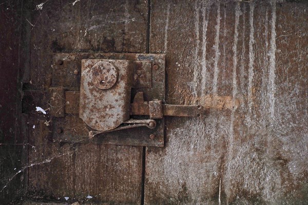 Rusty door lock with cobwebs on wooden door