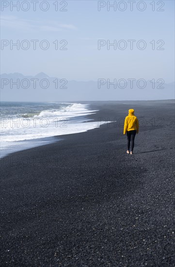Woman walking on a black sand beach