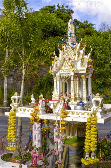 Buddhist spirit house Spirit house with offerings and floral decorations