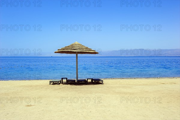 Abandoned empty beach chairs under sunshade on empty beach without tourists in lockdown