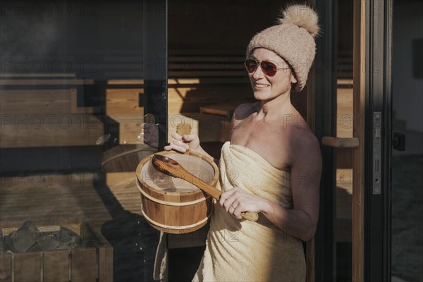 Woman with infusion tub in front of the sauna