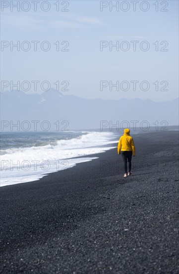 Woman walking on a black sand beach