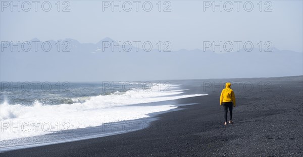 Woman walking on a black sand beach